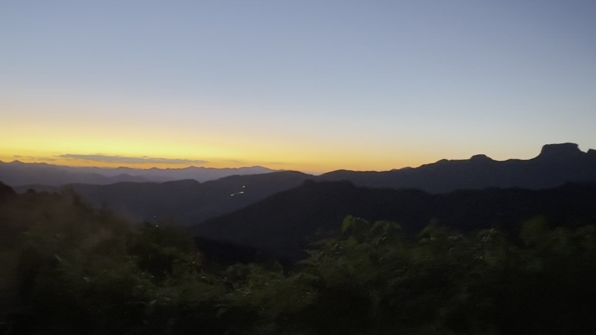 A serra em silhueta ao entardecer, com mata em primeiro plano